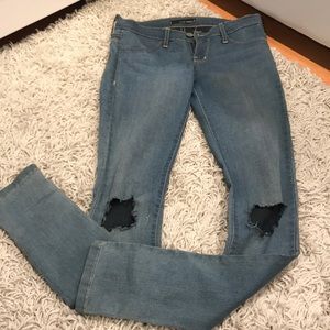 Low rise skinny jeans with holes in knees.